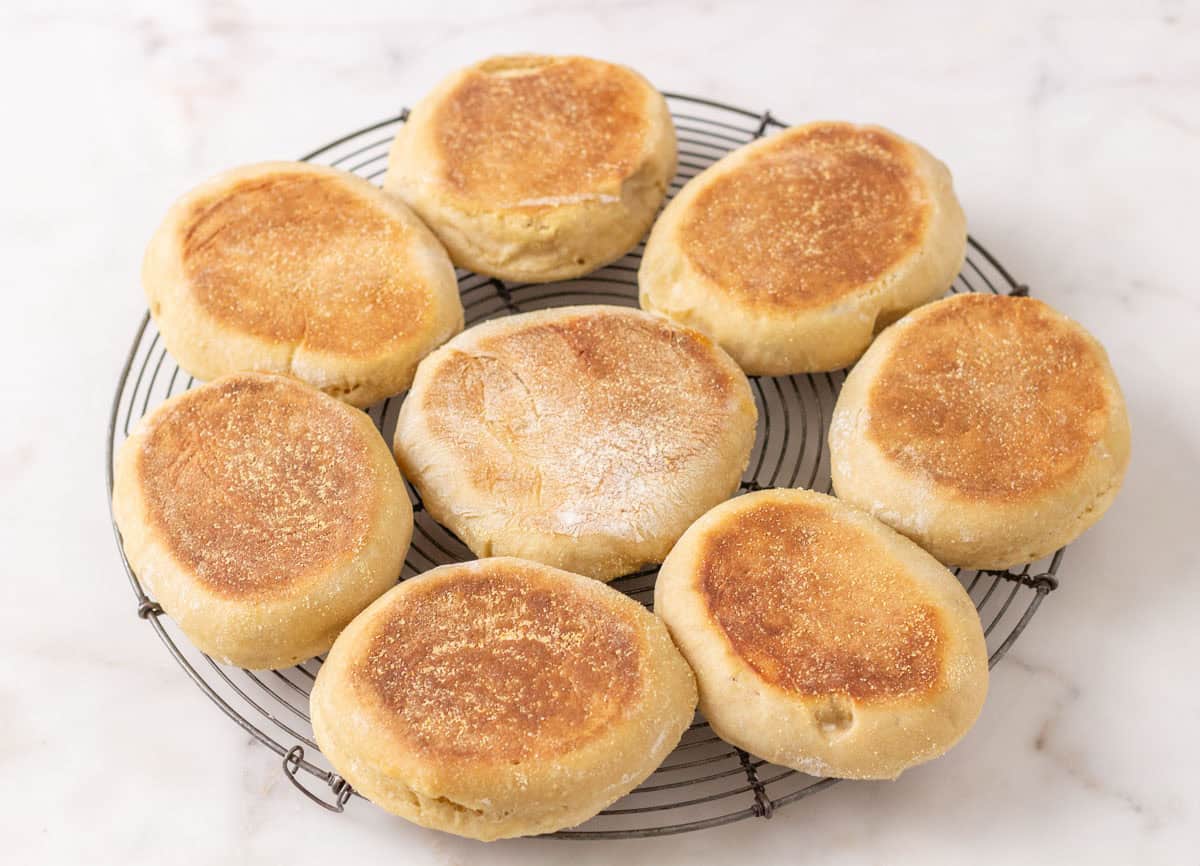 Sourdough Discard English Muffin Recipe | thewendthousekitchen.com Cooked English muffins on a round cooling grid.