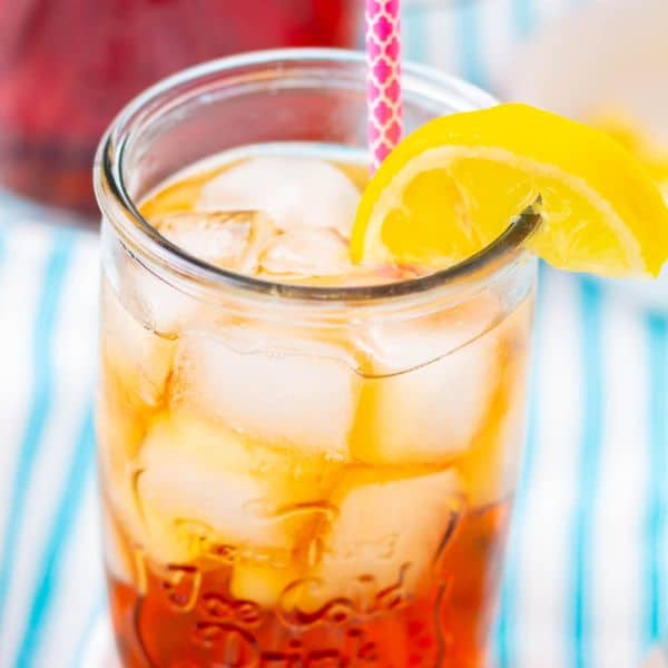 Southern sweet tea in a glass with ice with a lemon and a pink straw.