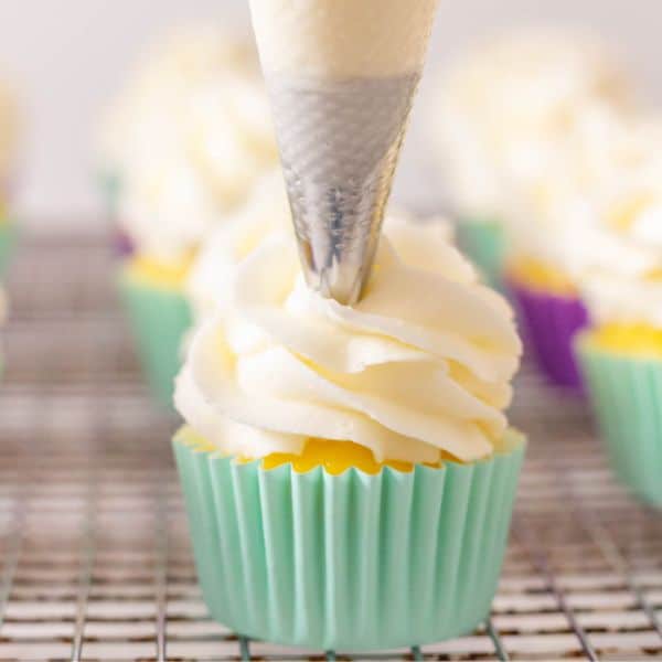Frosting a cupcake with a piping tip. Light turquoise cupcake liner and vanilla buttercream.
