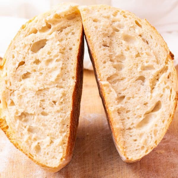 Artisan sourdough bread loaf cut in half and standing up.