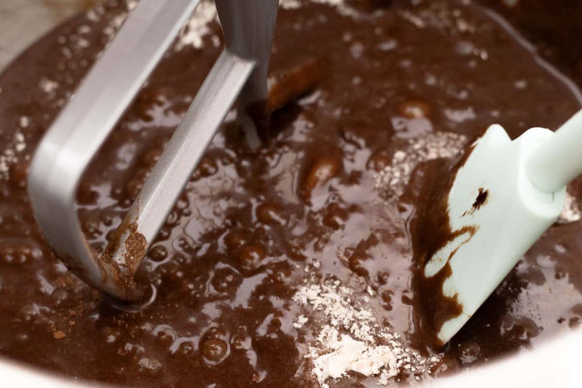 Chocolate Mint Cake with Mint Cream Cheese Frosting | thewendthousekitchen.com Chocolate cake batter partially mixed with a paddle attachment and shown with a mint green silicone spatula in the bowl of a stand mixer.