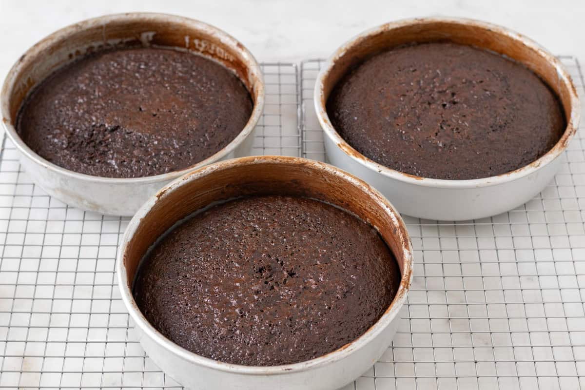 Chocolate Mint Cake with Mint Cream Cheese Frosting | thewendthousekitchen.com Three chocolate cakes cooling in their pans on a cooling grid.