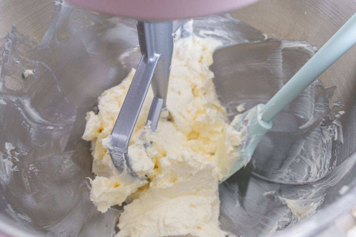 Chocolate Mint Cake with Mint Cream Cheese Frosting | thewendthousekitchen.com Butter and cream cheese partially mixed together with a paddle attachment in the bowl of a stand mixer with a mint green silicone spatula.
