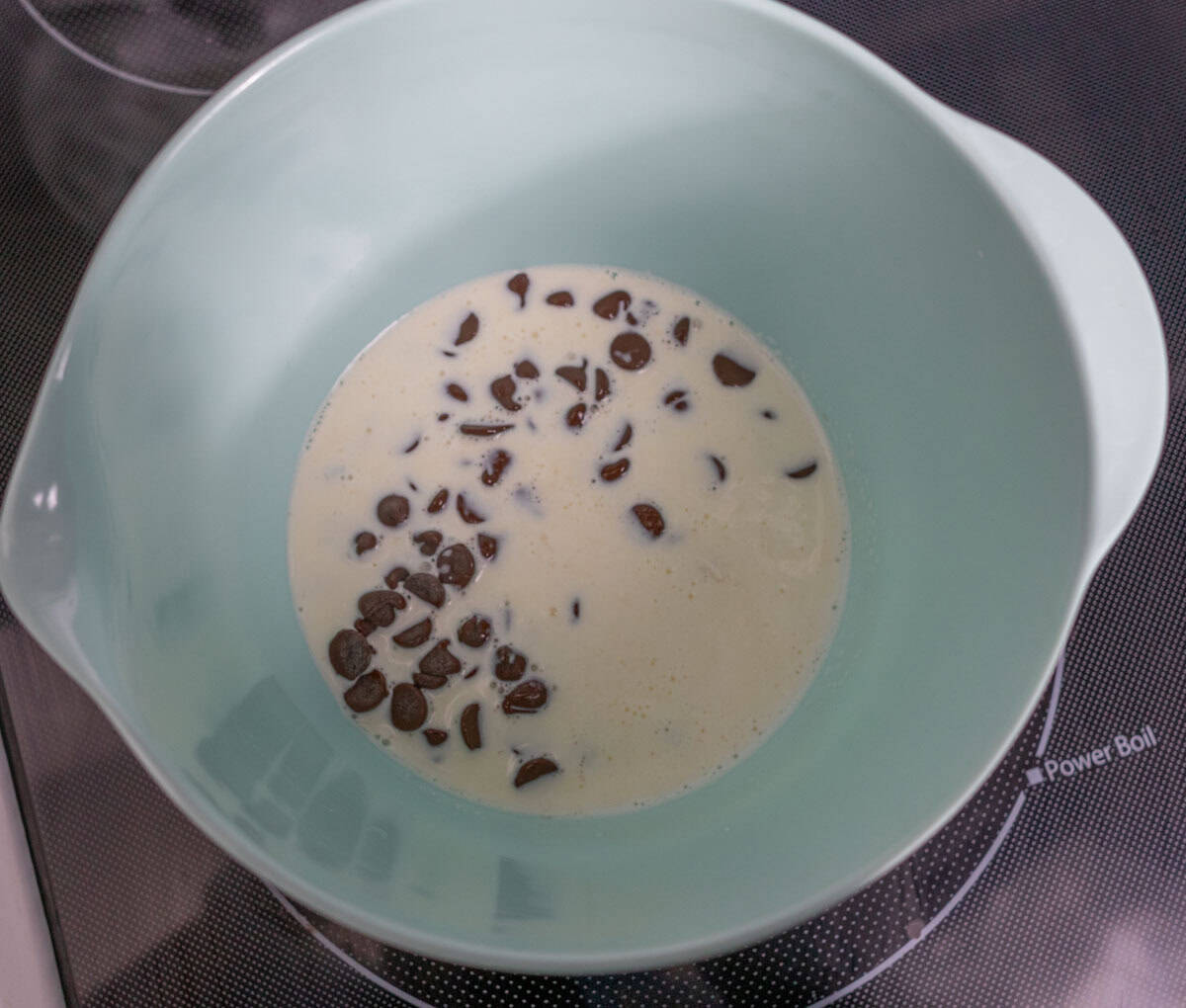 Chocolate Mint Cake with Mint Cream Cheese Frosting | thewendthousekitchen.com Hot heavy whipping cream in a mixing bowl with chocolate chips.