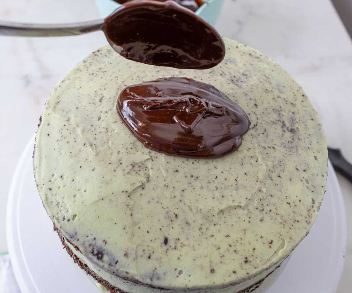 Chocolate Mint Cake with Mint Cream Cheese Frosting | thewendthousekitchen.com Spooning chocolate ganache onto chilled and crumb coated chocolate mint cake.