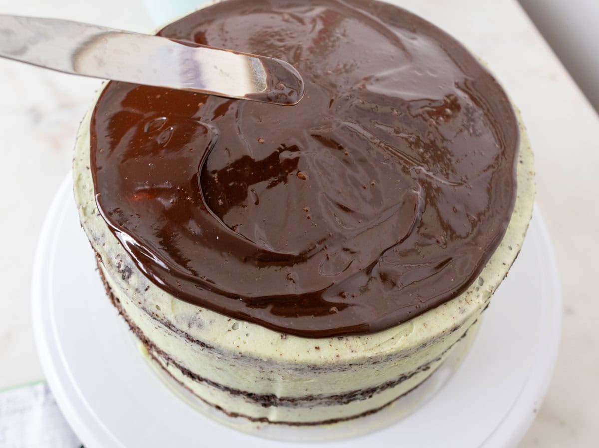 Chocolate Mint Cake with Mint Cream Cheese Frosting | thewendthousekitchen.com Spreading chocolate ganache with a small angled spatula onto crumb coated mint chocolate cake.