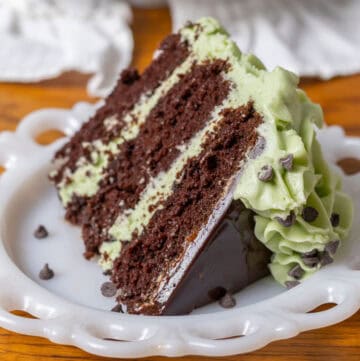 Piece of chocolate mint cake with green mint cream cheese frosting on a white plate.