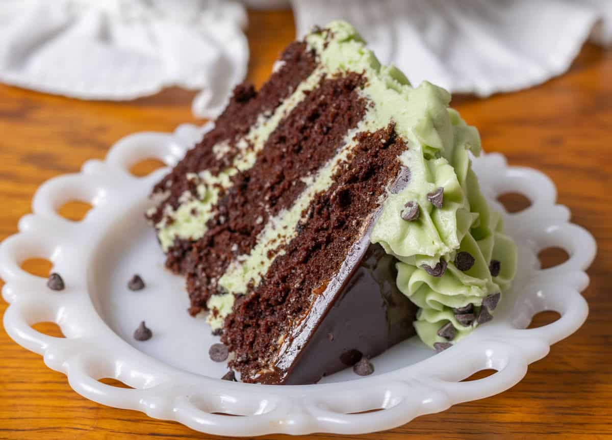 Piece of chocolate mint cake with green mint cream cheese frosting on a white plate.