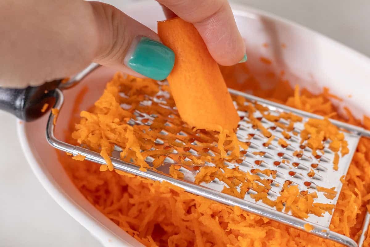 Carrot Cake Loaf Cake | thewendthousekitchen.com Shredding carrots with a grater.