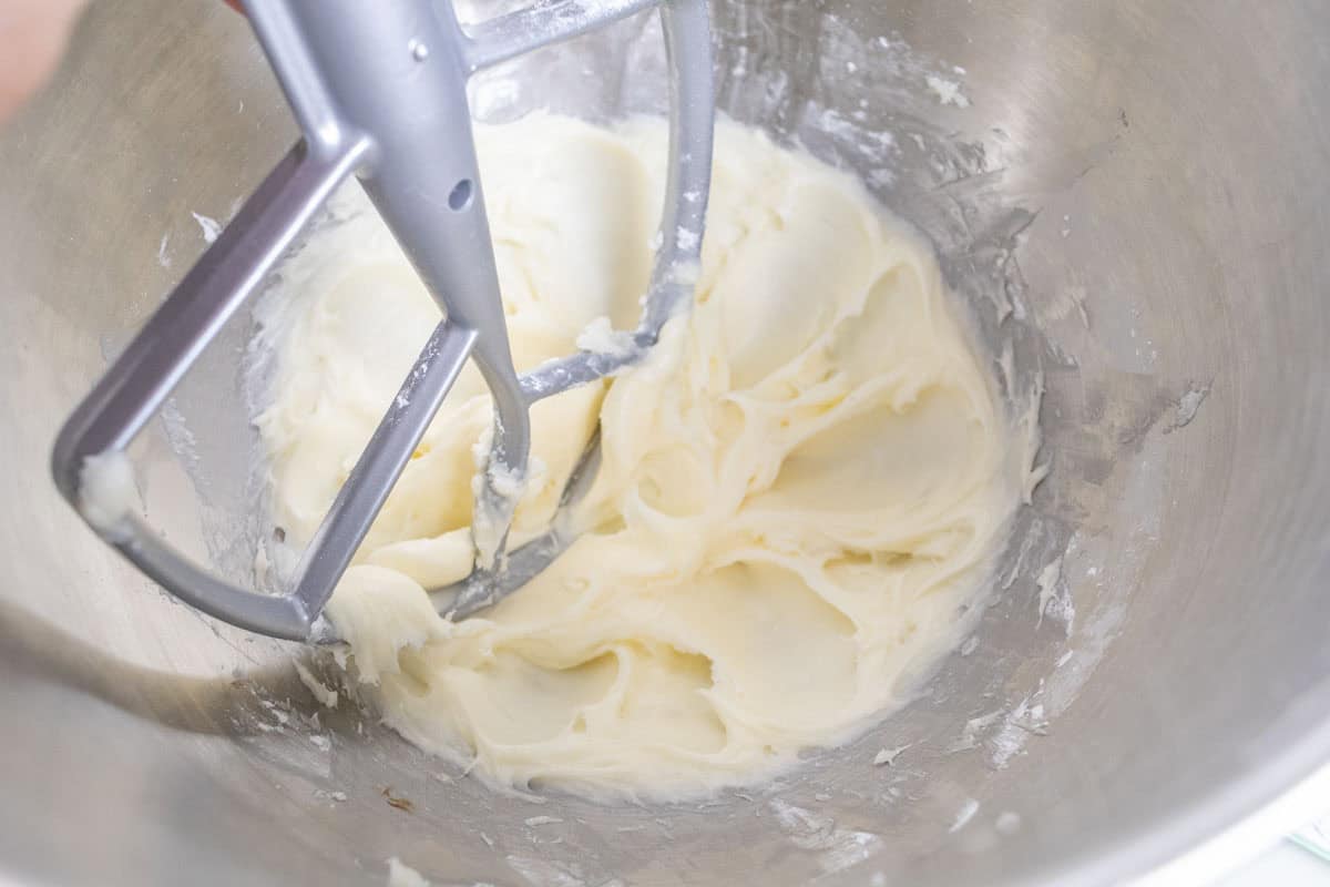 Carrot Cake Loaf Cake | thewendthousekitchen.com Cream cheese frosting in the bowl of a stand mixer with a paddle attachment.
