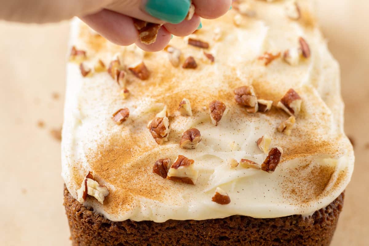 Carrot Cake Loaf Cake | thewendthousekitchen.com Adding nuts and cinnamon to the top of the frosted carrot loaf cake.