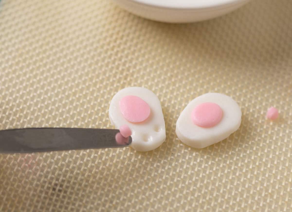 Bunny Cupcakes for Easter (Bunny Butt Cupcakes) | thewendthousekitche.com Using a small spatula to add the small bunny pads to the bunny paws.