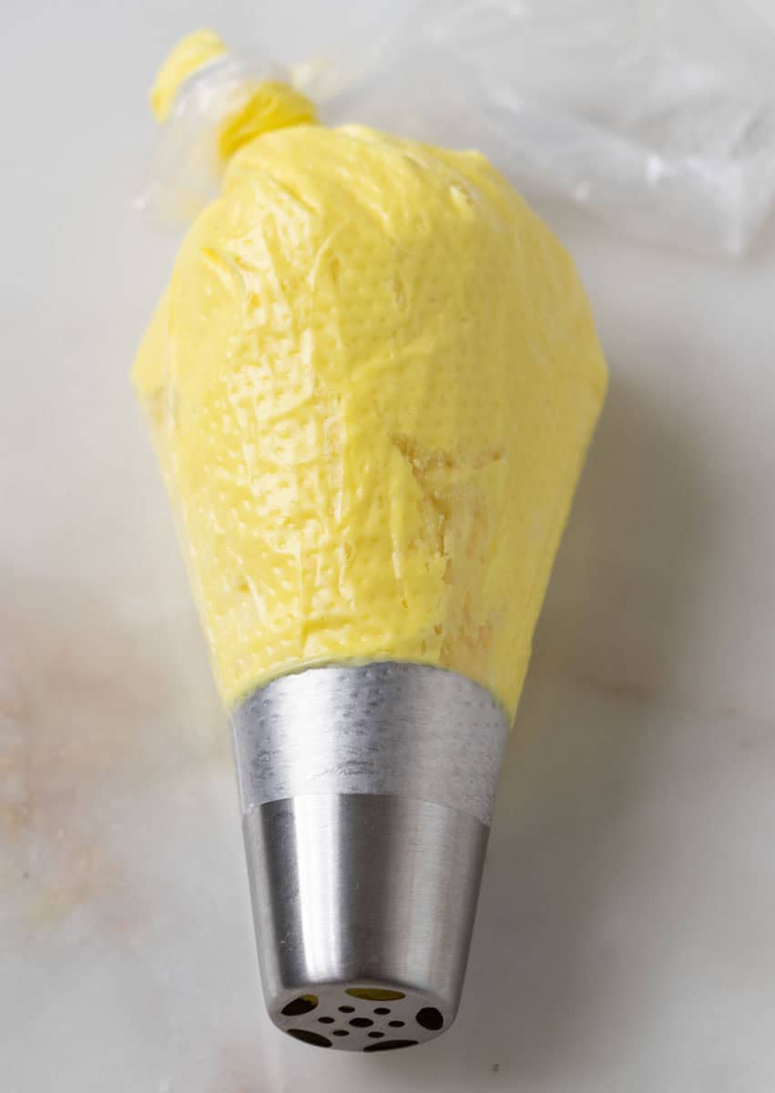 Bunny Cupcakes for Easter (Bunny Butt Cupcakes) | thewendthousekitchen.com A piping bag with a Russian piping tip filled with yellow buttercream.
