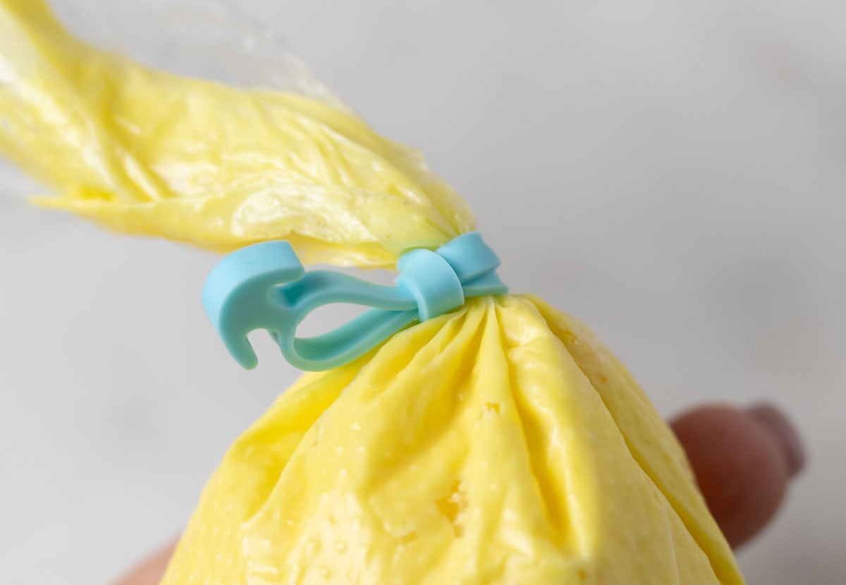 Bunny Cupcakes for Easter (Bunny Butt Cupcakes) | thewendthousekitchen.com A turquoise piping bag tie on a piping bag filled with yellow buttercream.