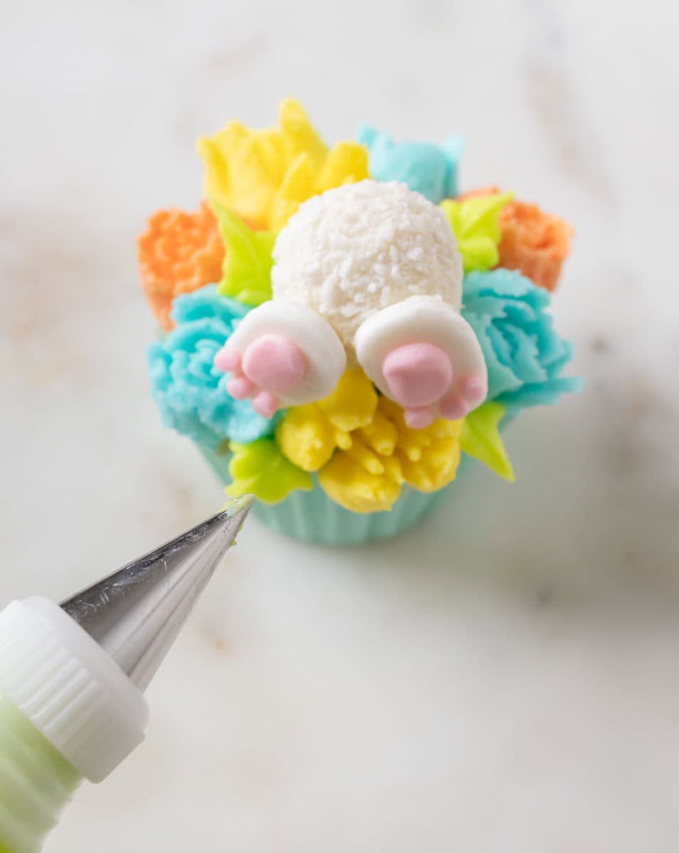 Bunny Cupcakes for Easter (Bunny Butt Cupcakes) | thewendthousekitchen.com Adding leaves to the buttercream flower cupcakes with green buttercream and a tip #352.