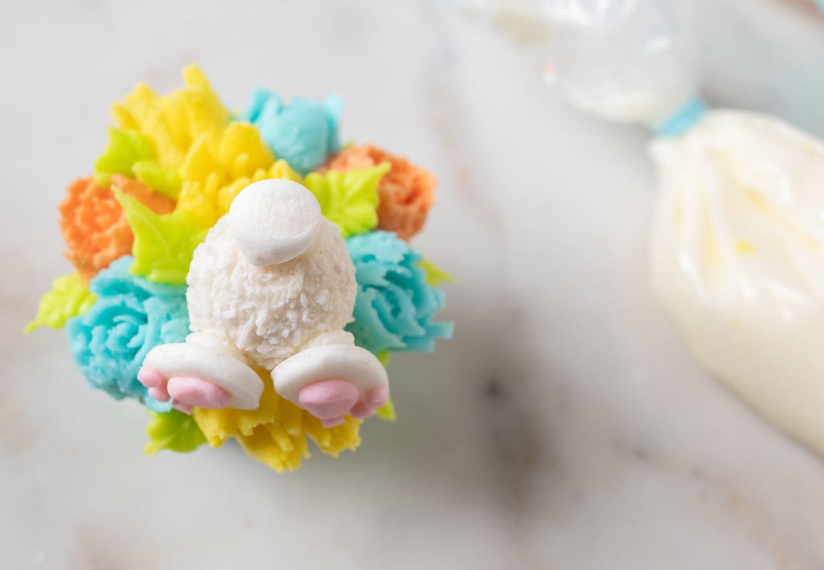 Bunny Cupcakes for Easter (Bunny Butt Cupcakes) | thewendthousekitchen.com A mini marshmallow on the back of a Rafaello candy on a decorated cupcake.