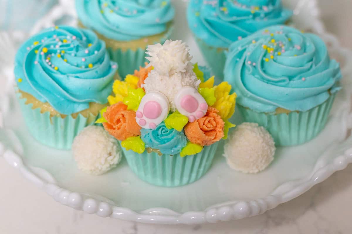 Bunny Cupcakes for Easter (Bunny Butt Cupcakes) | thewendthousekitchen.com bunny butt cupcake with Raffaello candies nex to it with more cupcakes in the background.
