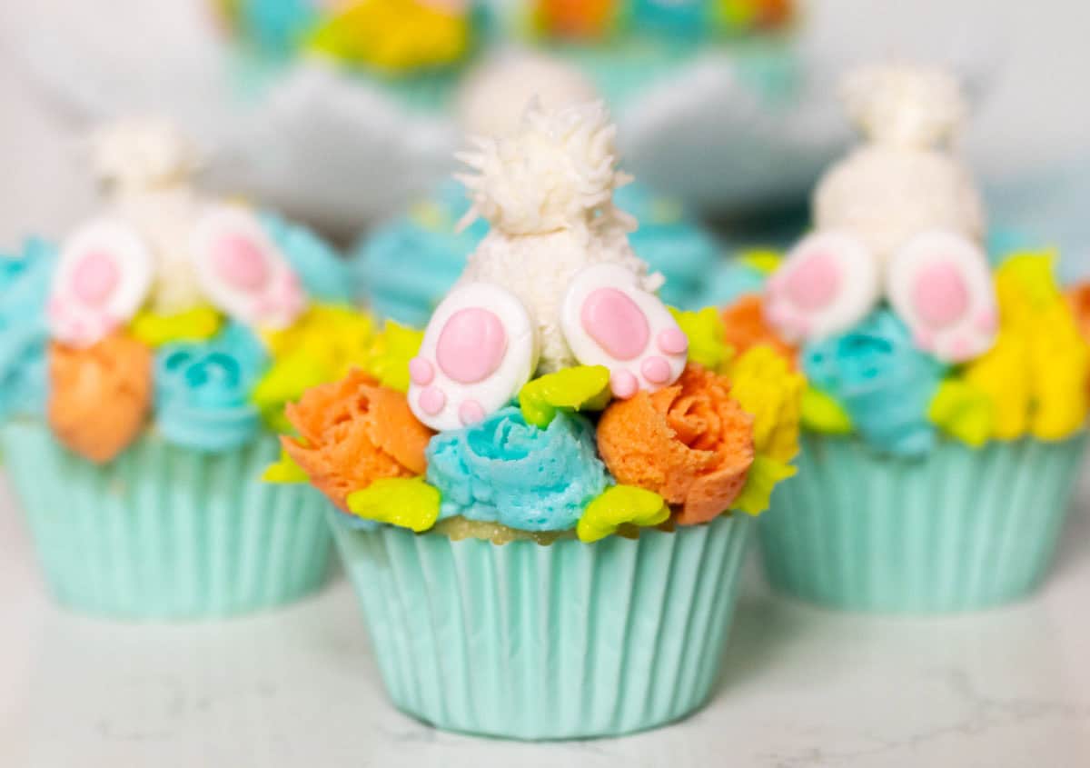 Bunny Cupcakes for Easter (Bunny Butt Cupcakes) | thewendthousekitchen.com Three bunny butt cupcakes with light turquoise, orange and yellow buttercream flowers.