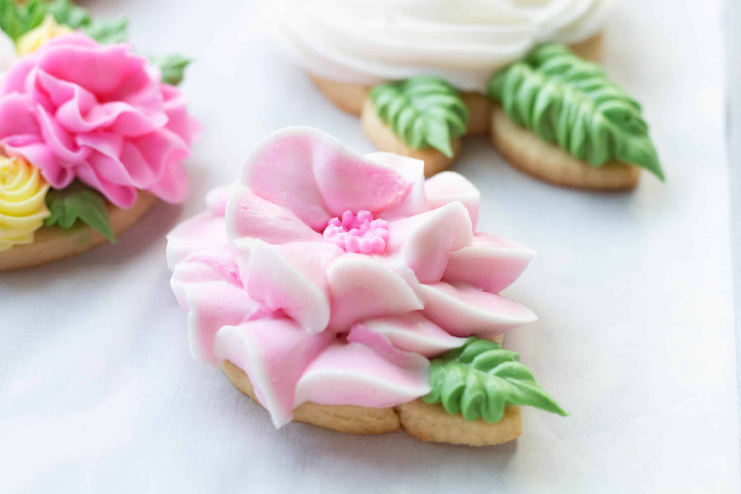 Decorated pink floral cookies with green leaves.