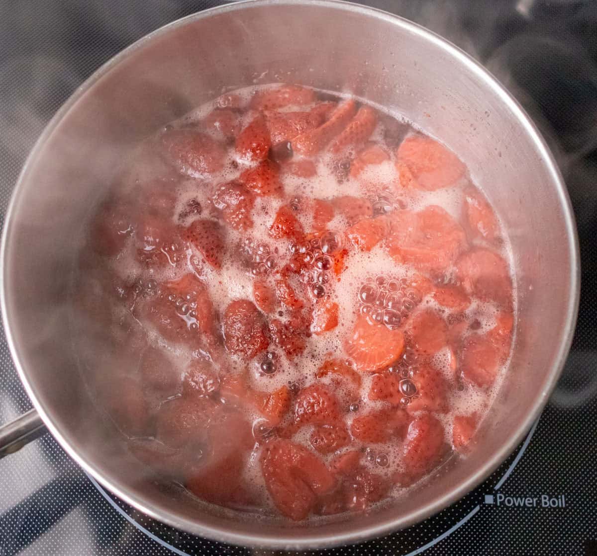 How To Make Strawberry Sauce | thewendthousekitchen.com Strawberries, water and sugar simmering in a medium saucepan.