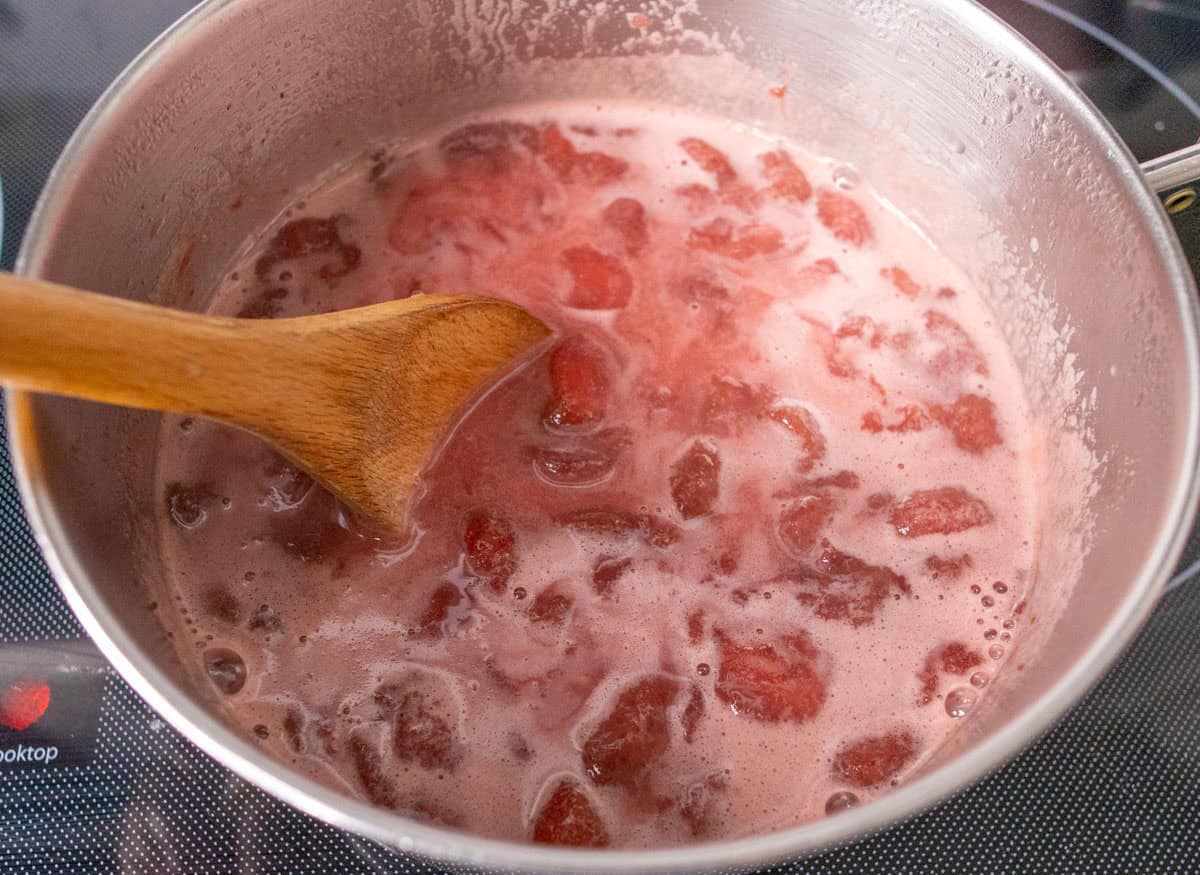 How To Make Strawberry Sauce | thewendthousekitchen.com Cornstarch slurry stirred into the strawberries, water and sugar with a wooden spoon.