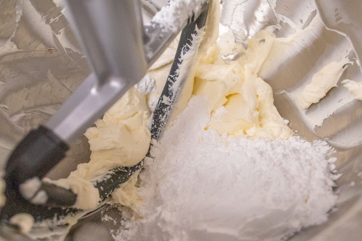 3 Ingredient No Bake Cheesecake | thewendthousekitchen.com Powdered sugar added to cream cheese in the bowl of a stand mixer with a paddle attachment.