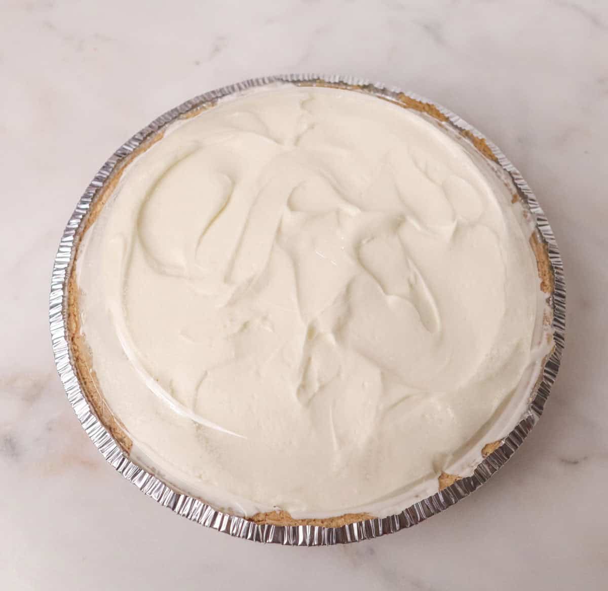 3 Ingredient No Bake Cheesecake | thewendthousekitchen.com Plastic lid on top of cheesecake ready for the refrigerator.