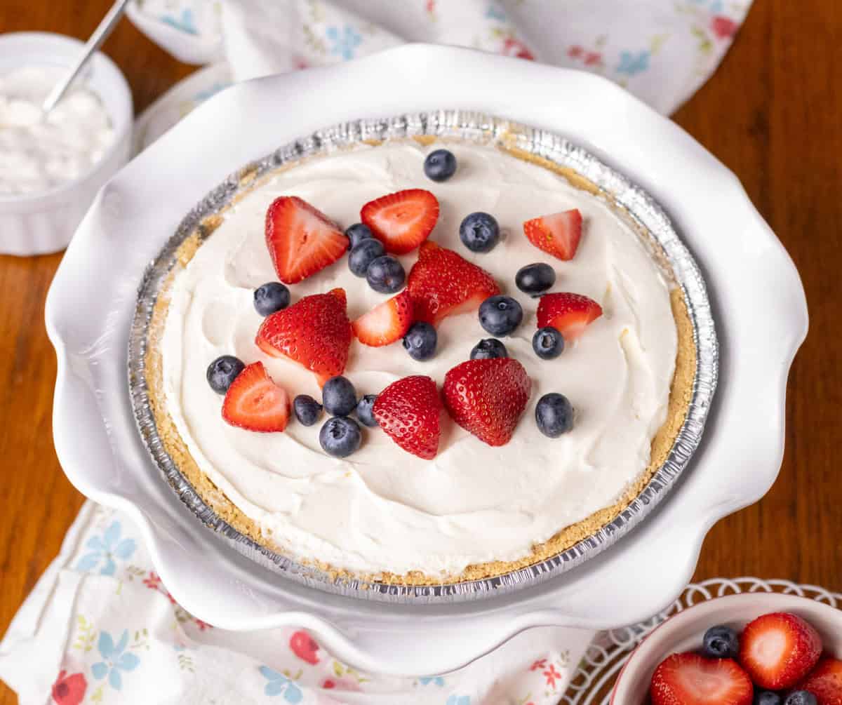 3 Ingredient No Bake Cheesecake | thewendthousekitchen.com No bake cheesecake in a premade graham cracker crust with fresh cut up strawberries and fresh blueberries on top.