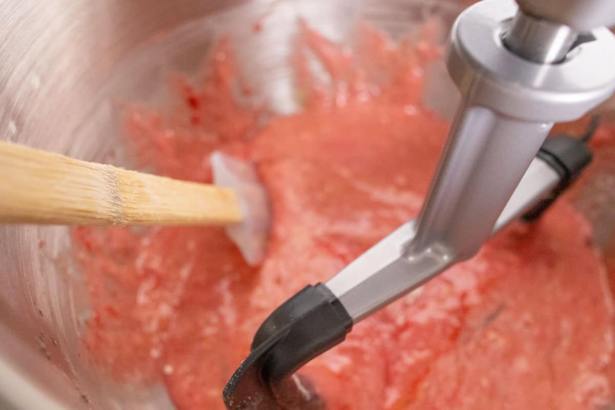 Strawberry Crunch Cake | thewendthousekitchen.com Mixing strawberry cake ingredients in the bowl of a stand mixer and scraping down the sides of the bowl with a silicone spatula.