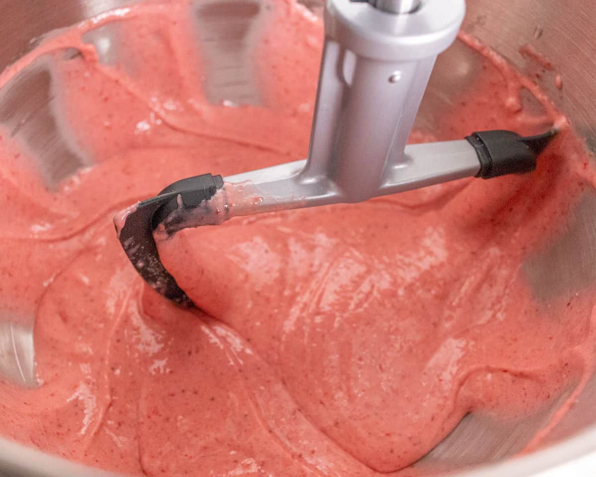 Strawberry Crunch Cake | thewendthousekitchen.com Mixing strawberry cake ingredients in the bowl of a stand mixer with a paddle attachment.