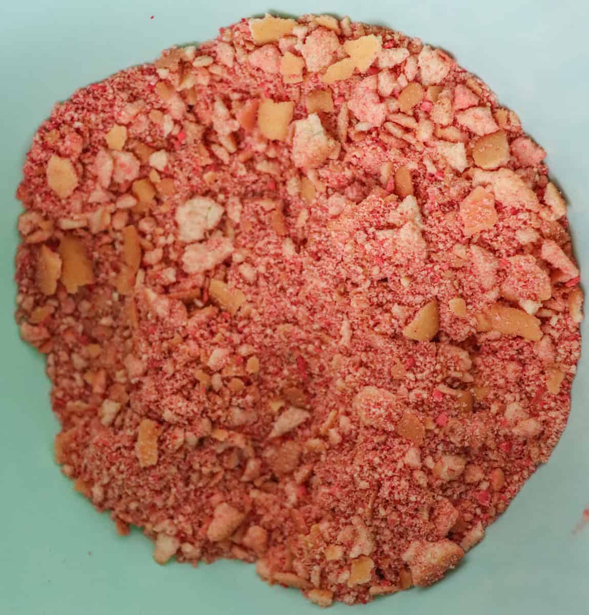Strawberry Crunch Cake | thewendthousekitchen.com Crushed vanilla wafers, freeze-dried strawberry powder and salt mixed together in a light turquoise bowl.