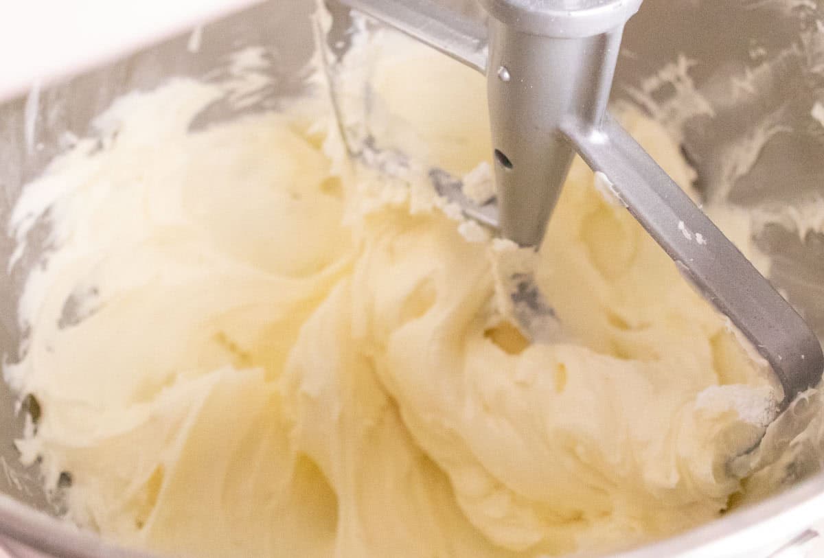 Strawberry Crunch Cake | thewendthousekitchen.com Whipped buttercream in the bowl of a stand mixer with a paddle attachment.