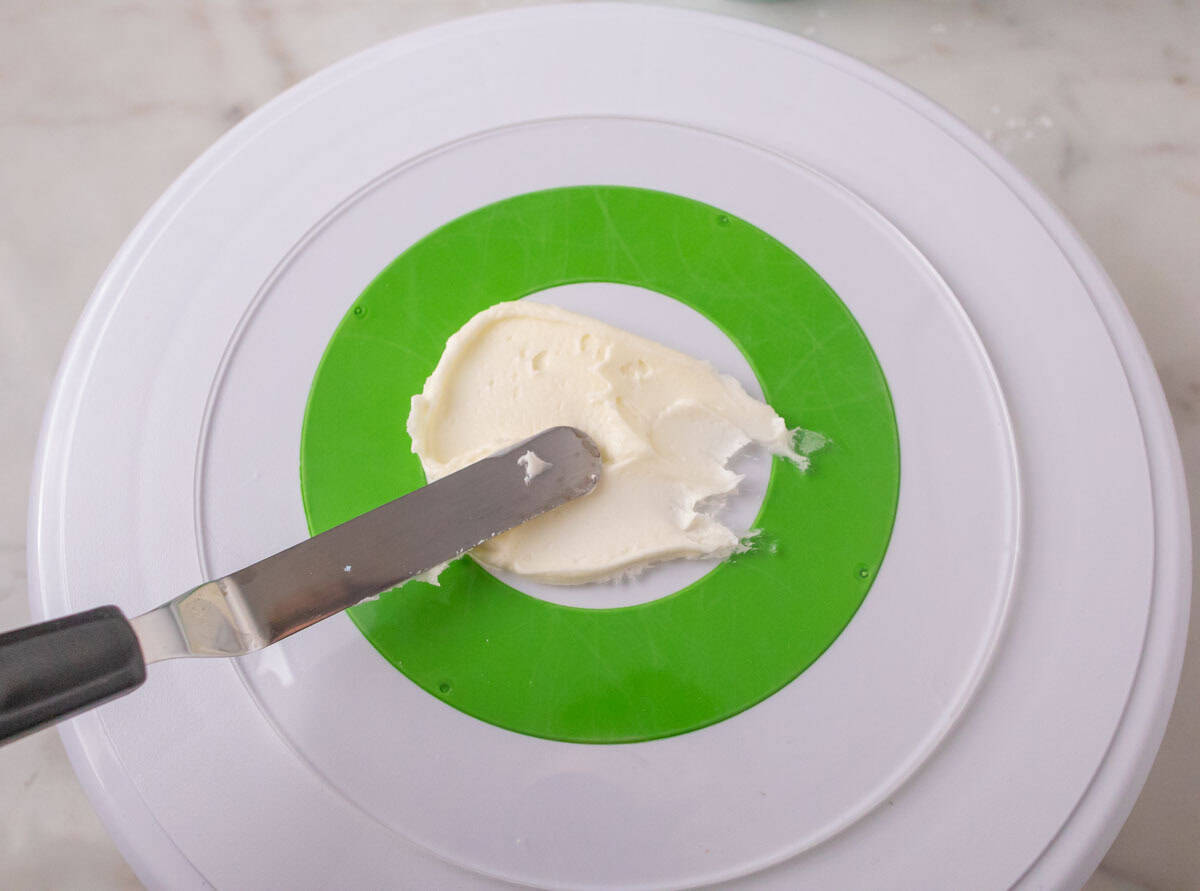 Strawberry Crunch Cake | thewendthousekitchen.com Spreading plain buttercream on the middle of an acrylic disc.