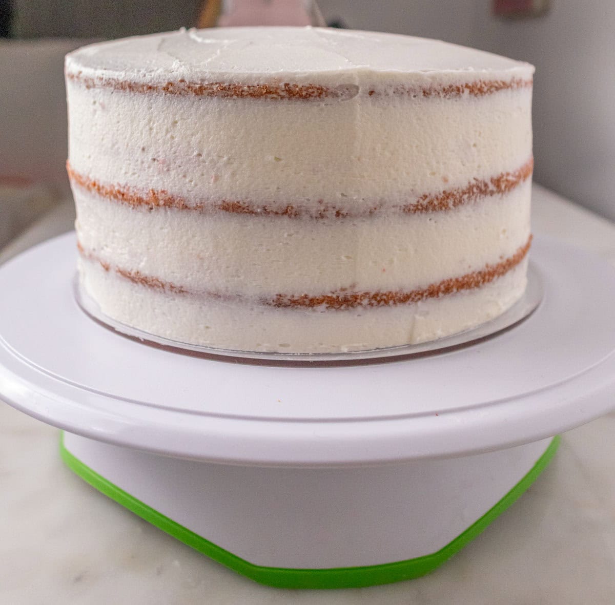Strawberry Crunch Cake | thewendthousekitchen.com An 8-inch, 3-layer cake crumb-coated on an acrylic cake circle on a cake turntable.