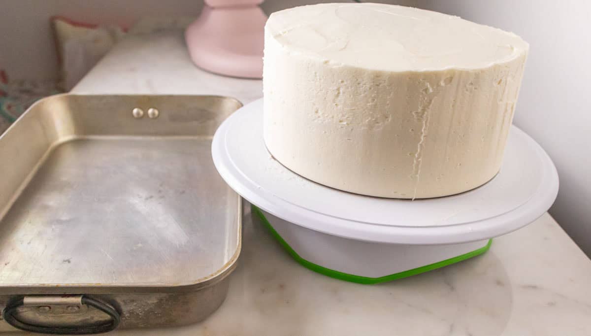 Strawberry Crunch Cake | thewendthousekitchen.com A metal 9 x 13-inch roasting pan next to a frosted cake.