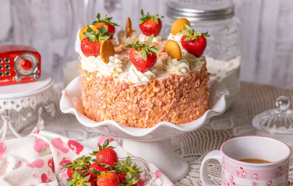 Strawberry Crunch Cake | thewendthousekitchen.com Strawberry crunch cake with fresh strawberries on a white cake pedestal.